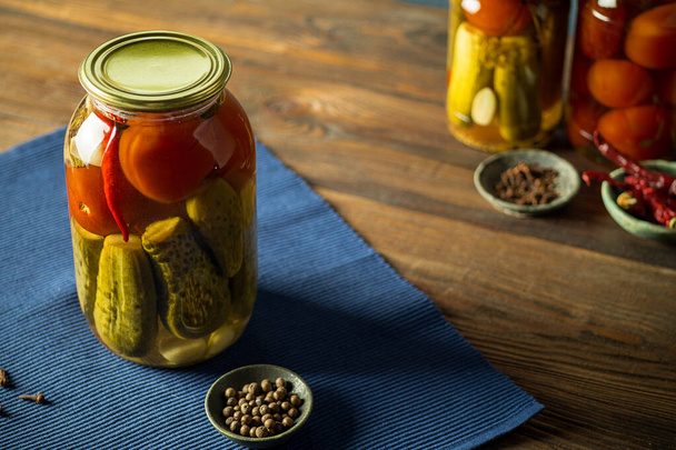 Tomatoes and cucumbers fermented in a glass jar and spices. - Zdjęcie, obraz
