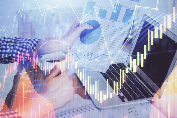 Double exposure of stock graph with businessman typing on computer in office on background. Concept of hard work. - Фото, изображение