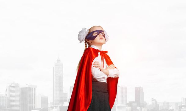 Vertrouwen kindje in masker en cape speelt coole superheld - Foto, afbeelding
