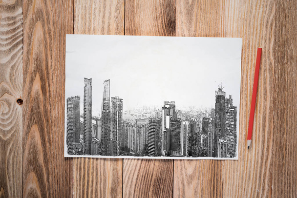 Modern city center pencil draw. Panorama of urban modern city with high skyscrapers sketch on wooden surface. Sheet of paper on textured natural wooden background. Architecture agency concept - Photo, Image