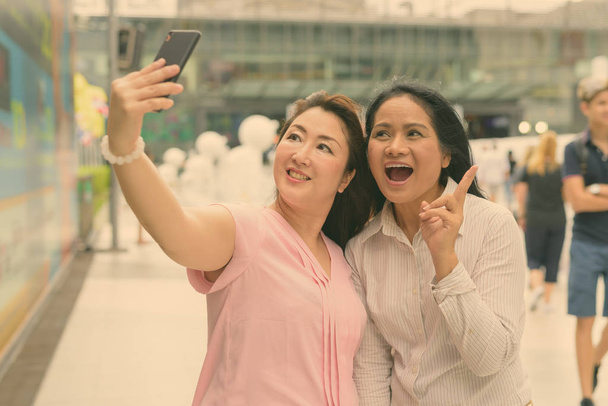 Two mature Asian women together outside the mall in Bangkok city - Foto, Imagen