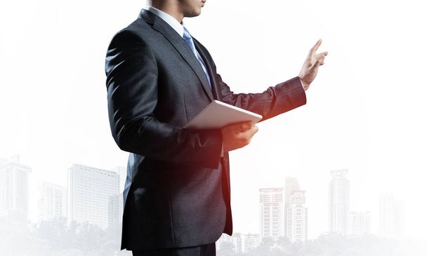 Business expert standing and pointing copy space. Accounting and consulting. Side view of man in formal wear on background foggy cityscape. Financial specialist with raised hand promotion mockup. - Valokuva, kuva