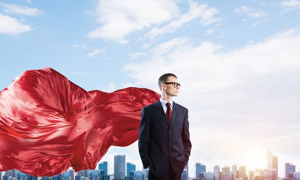 Jovem empresário confiante vestindo capa vermelha contra o pano de fundo da cidade moderna - Foto, Imagem