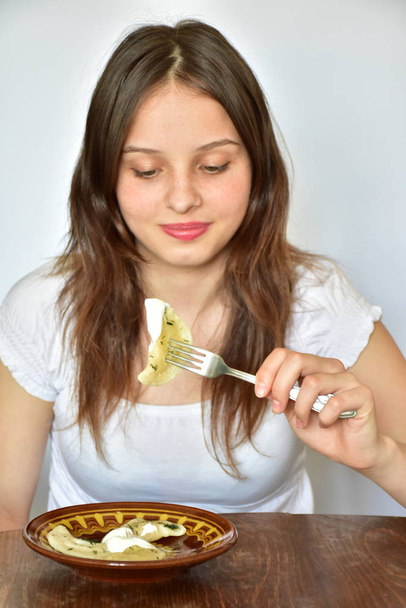 Το κορίτσι τρώει ζυμαρικά. Ουκρανική εθνική κουζίνα. Βφρτνίκι και πελμένι. - Φωτογραφία, εικόνα
