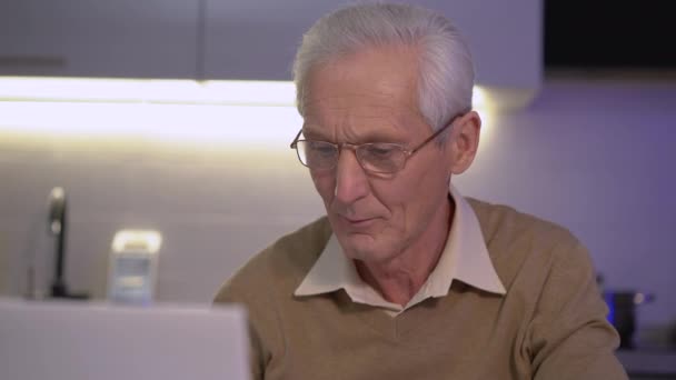 Old retired man in eyeglasses relaxing, using laptop at home, internet project - Filmmaterial, Video