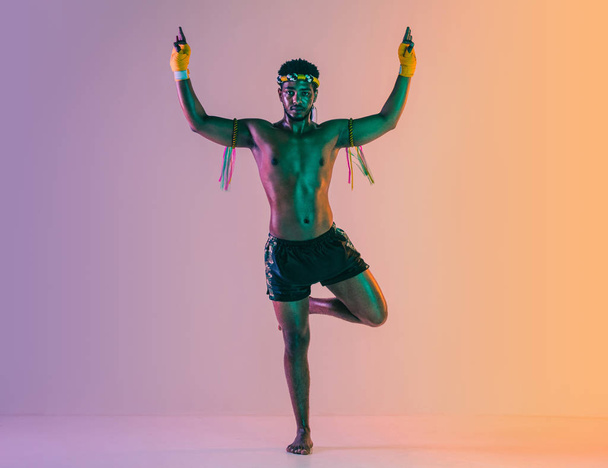 Muay thai. Young man exercising thai boxing on gradient background - Foto, afbeelding