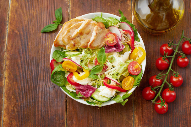 Fresh salad with tomatoes and chicken with bell peppers and radishes with mozzarella cheese on wooden background   - Fotó, kép