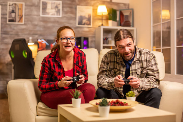 Gamers paar spelen video games op de TV met draadloze controllers in handen - Foto, afbeelding