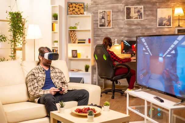 Чоловік геймер використовує гарнітуру VR для відтворення відеоігор у вітальні
 - Фото, зображення