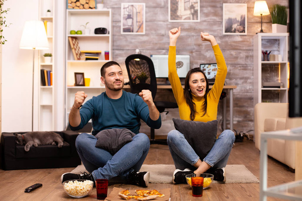Couple assis sur le sol et regarder la télévision dans leur salon
 - Photo, image