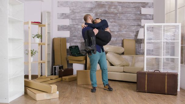 Excited boyfriend spining his girlfriend in their new apartment - Φωτογραφία, εικόνα
