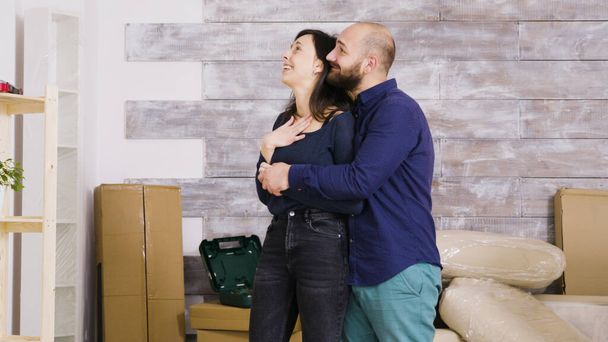 Счастливая молодая пара обнимает друг друга в своей новой квартире
 - Фото, изображение