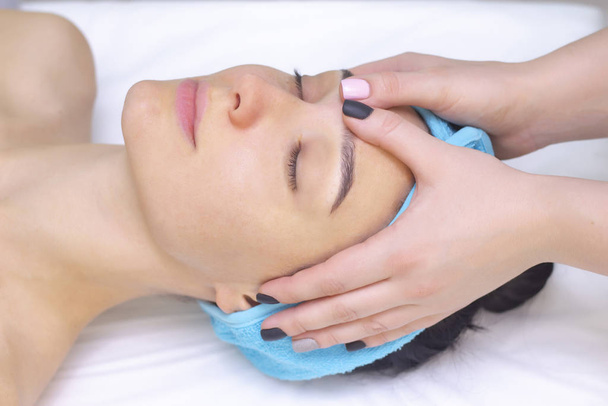 Young woman enjoying massage in spa salon. Face massage. Closeup of young woman getting spa massage treatment at beauty spa salon.Spa skin and body care. Facial beauty treatment.Cosmetology.  - Fotó, kép