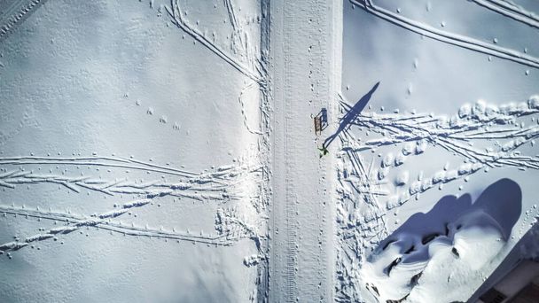 Luftaufnahme einer jungen Frau, die einen Schlitten durch den Schnee zieht - Foto, Bild