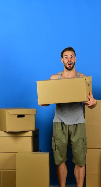 Man standing among cardboard boxes and holding one - Фото, зображення