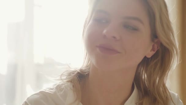 Close-up portrait of attractive Caucasian woman in in sunlight. Beautiful girl resting in bedroom in the morning. Tranquility, lifestyle, relaxation. - Filmagem, Vídeo