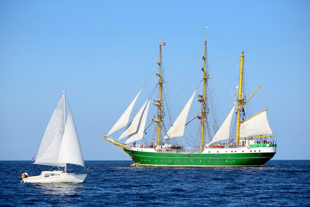 Old historical tall ship and a yacht with sails in blue sea - Photo, Image