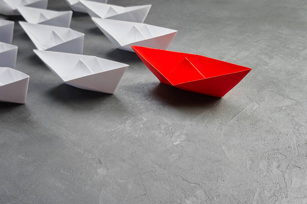 Üzleti vezetés koncepció, Paper Boat, a legfontosabb vélemény Leader, a koncepció a befolyás. Egy piros papírhajó, mint a vezető, amely a fehér hajók felé vezet szürke beton alapon, c - Fotó, kép