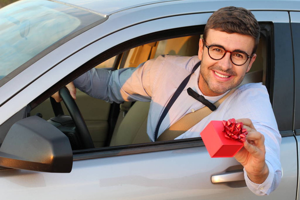 Όμορφος χαμογελαστός άνδρας με γυαλιά οδήγησης αυτοκίνητο παρουσίαση κουτί δώρου - Φωτογραφία, εικόνα