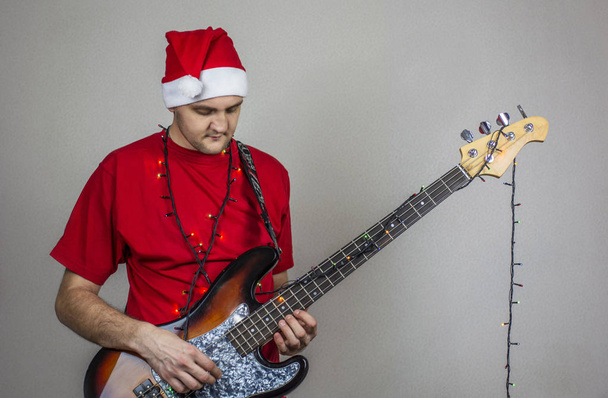 молодий хлопець у різдвяній шапці та червоній футболці з гітарою
  - Фото, зображення