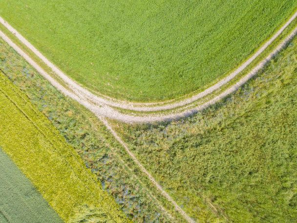Vista aérea de la carretera a lo largo de dos campos agrícolas en verano
 - Foto, Imagen