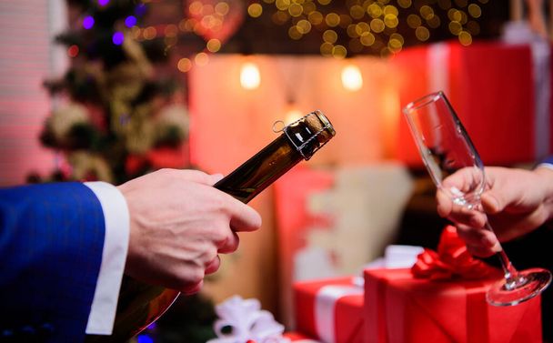 Male hands opening champagne bottle pouring glasses christmas decorations background. Drink champagne or sparkling wine. Celebrate new year with champagne. Toast and cheers concept. Lets celebrate - Foto, imagen