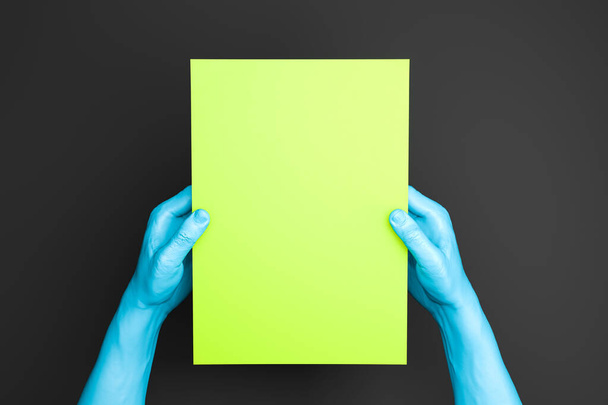 Realistic White Human Hands Holding Light Green Blank Paper Sheet With Empty Space On Black Background. 3d rendering - Фото, зображення
