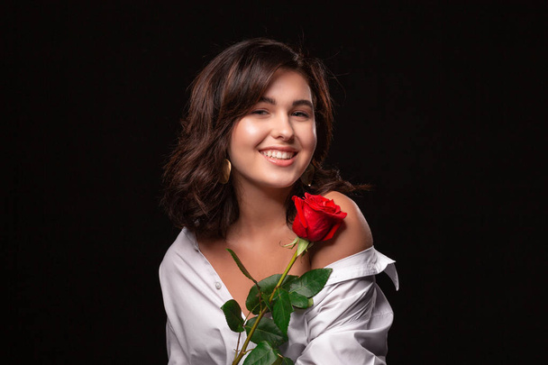Красивая женщина с ярким макияжем позировать изолированы на черном фоне с красной розой
. - Фото, изображение