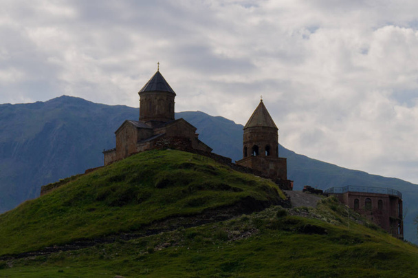 Iglesia Trinidad. Kazbek Stepantsminda. Georgia. Templo en las montañas contra el telón de fondo de las montañas
. - Foto, imagen