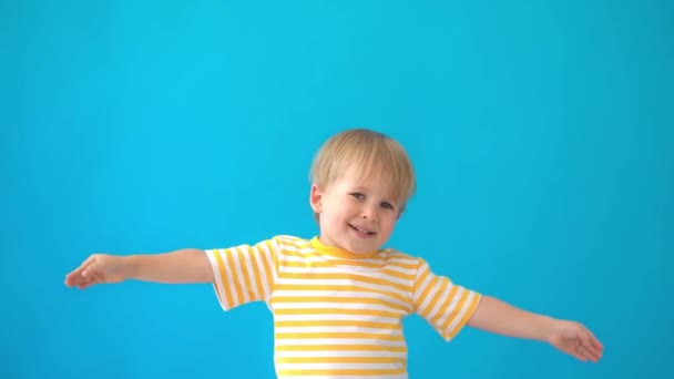Happy child having fun. Kid laughing against blue background. Summer vacation and travel concept. Slow motion - Metraje, vídeo