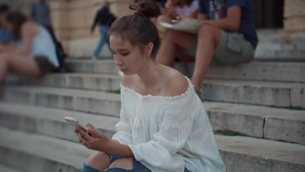 opiskelijat istuvat kiviportaat, chattailuun verkossa älypuhelimilla
 - Materiaali, video