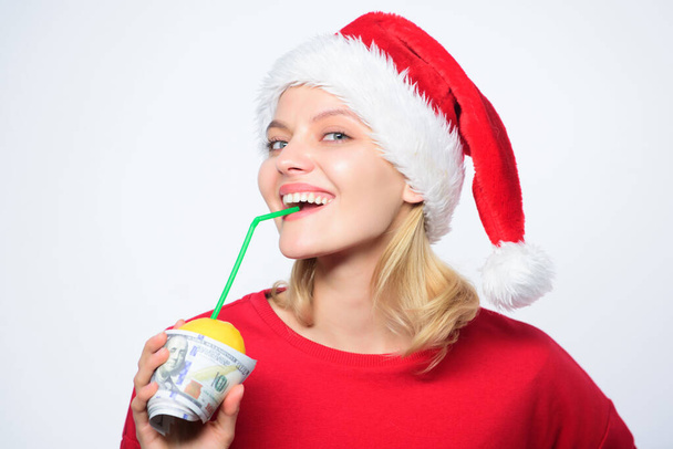 Christmas lemonade punch. Totally natural lemonade. Girl with lemonade and money. Fresh lemonade drink with straw. Symbol of wealth and richness. Girl santa hat drink juice lemon wrapped in banknote - Foto, afbeelding