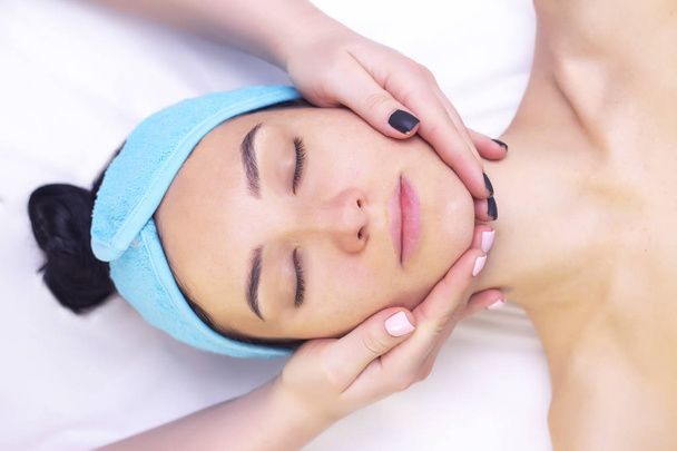 Young woman enjoying massage in spa salon. Face massage. Closeup of young woman getting spa massage treatment at beauty spa salon.Spa skin and body care. Facial beauty treatment.Cosmetology.  - Valokuva, kuva
