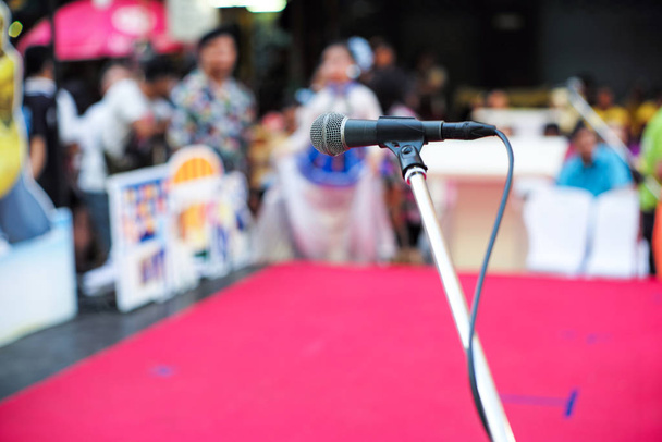Selectieve focus op microfoon op het podium met wazig publiek op de achtergrond - Foto, afbeelding