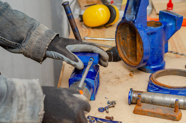 Ouvrier homme démantèle vieux étau métallique dans l'atelier
 - Photo, image