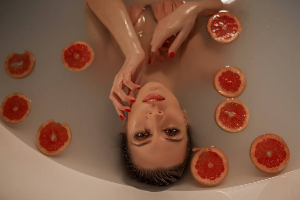 Portrait de femme sexy dans un bain avec lait et cercles de pamplemousse
 - Photo, image