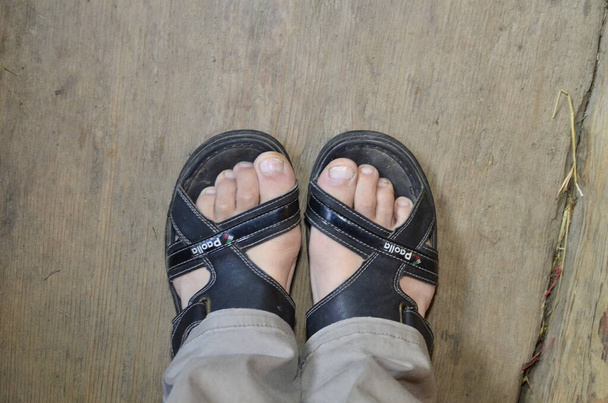 zbliżenie mężczyźni jedzenie noszenie oryginalne sandały skórzane buty lub vintage skórzane sandały buty na betonowej drodze - Zdjęcie, obraz
