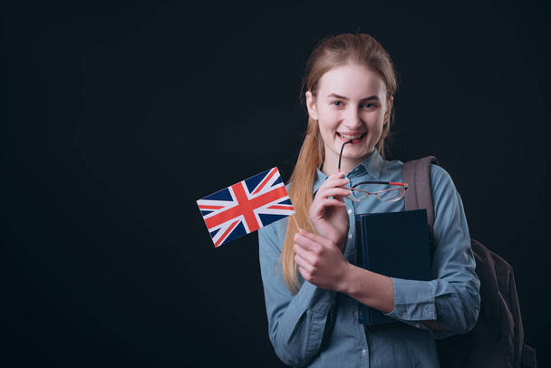 Usmívající se zázvor angličtina student dotýkající se její ret s brýlemi sluchátko - Fotografie, Obrázek