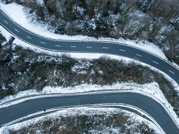 Vue aérienne d'une route sinueuse traversant un paysage enneigé en montagne suisse
 - Photo, image