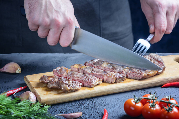 Chef cuts beef steak. Tasty meat of medium roast - Photo, Image