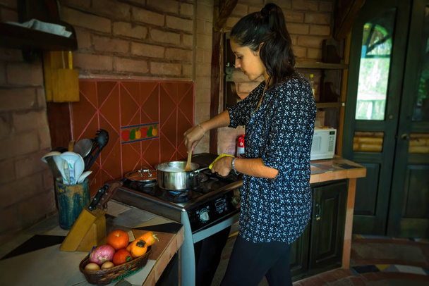 温暖な気候の家で一般的な屋外キッチンで調理する若い女性 - 写真・画像