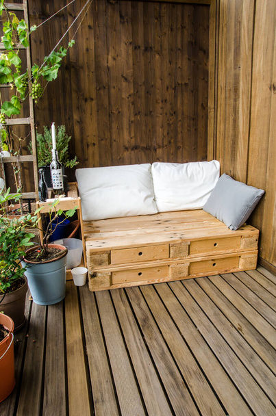 Sofá de paletes de madeira acolhedor na varanda
 - Foto, Imagem