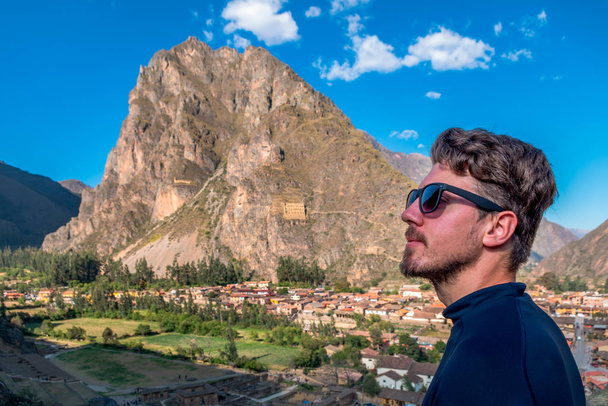 Muž turista v profilu se slunečními brýlemi, s pozadím města Ollantaytambo, Sacred Valley of the Incas. - Fotografie, Obrázek
