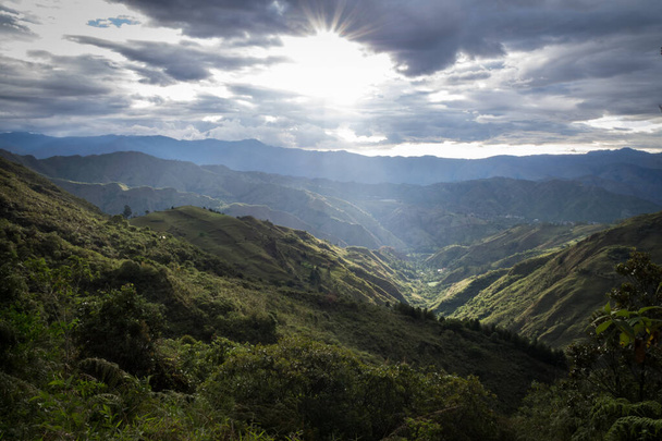 Vista panorâmica da serra equatoriana ao pôr do sol. Há grandes nuvens, montanhas, arbustos e árvores
. - Foto, Imagem