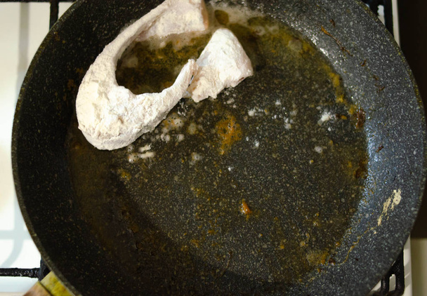 Pesce in pastella. I pezzi di pesce nella farina vengono fritti in una padella con il burro. Brucia. Pericolo Cena pesce fritto
. - Foto, immagini