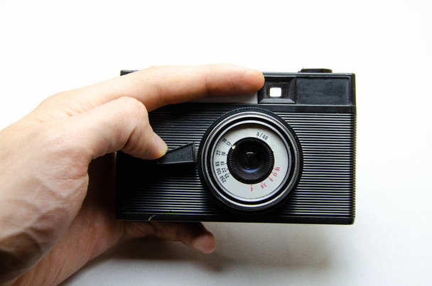 Παλιά κάμερα. Κάμερα σπανιότητας σε λευκό φόντο. Μια κάμερα σε χέρια μούσα, οπλίζοντας. Σοβιετικός φωτογραφικός εξοπλισμός. Η κάμερα σε μακροεντολή, φακό, μέσα, λεπτομέρειες  - Φωτογραφία, εικόνα