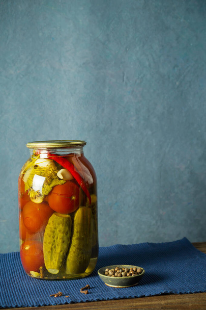 Bank with a variety of fermented cucumbers and tomatoes with seasonings. - Foto, afbeelding