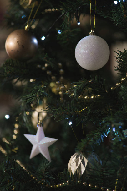 Nahaufnahme eines geschmückten Weihnachtsbaums mit goldenen und weißen Kugeln und Sternen - Foto, Bild