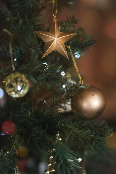 Χρυσή διακόσμηση με αστέρια και μπάλες σε χριστουγεννιάτικο δέντρο.  - Φωτογραφία, εικόνα