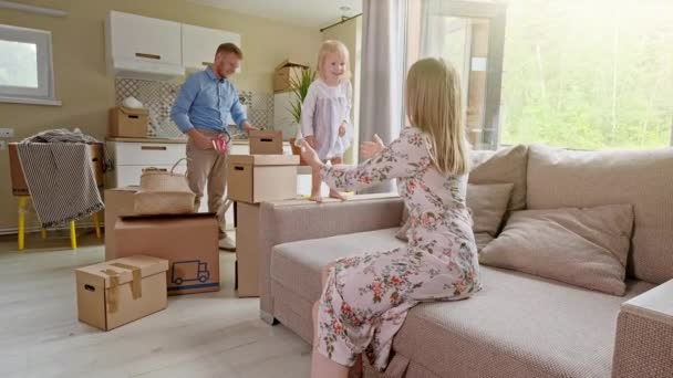 Active Family Group Move in Rent Real Estate. Positive Looking at Relocating or Unpacking of Carton Pack by Playful Family. Little girl jumps on hands to mom. Enjoying Life or Dream - Footage, Video
